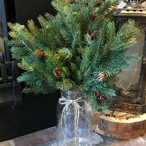 A bouquet of artificial pine sprays in a mason jar for Christmas.