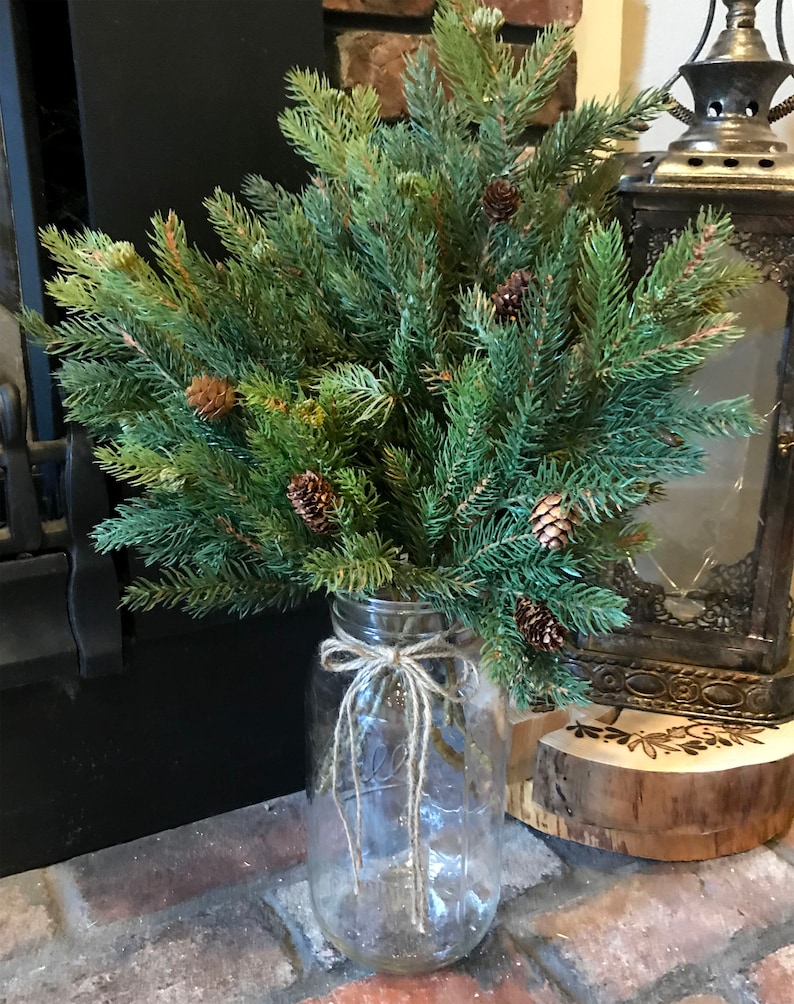 A bouquet of artificial pine sprays in a mason jar for Christmas.