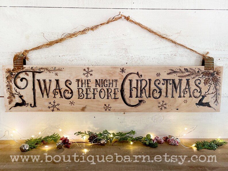 A horizontal wood sign. Twas the night before Christmas and reindeer are wood burned decoratively. The sign hangs with a piece of rope.