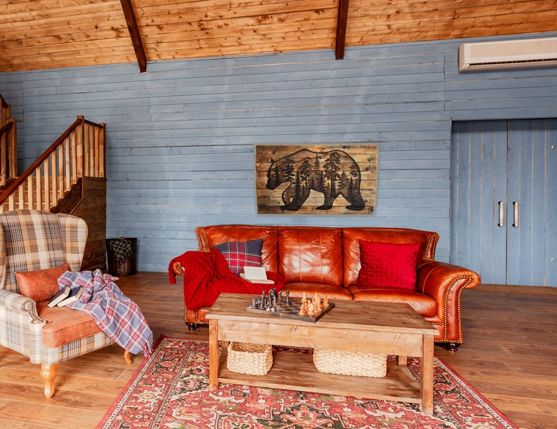 This image shows a handmade piece of rustic wall decor. It features a large bear with a scenic forest inside it. All the artwork is wood-burned by hand onto a pallet of reclaimed wood.