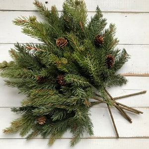 A bouquet of artificial Christmas pine sprays on a farmhouse fence.