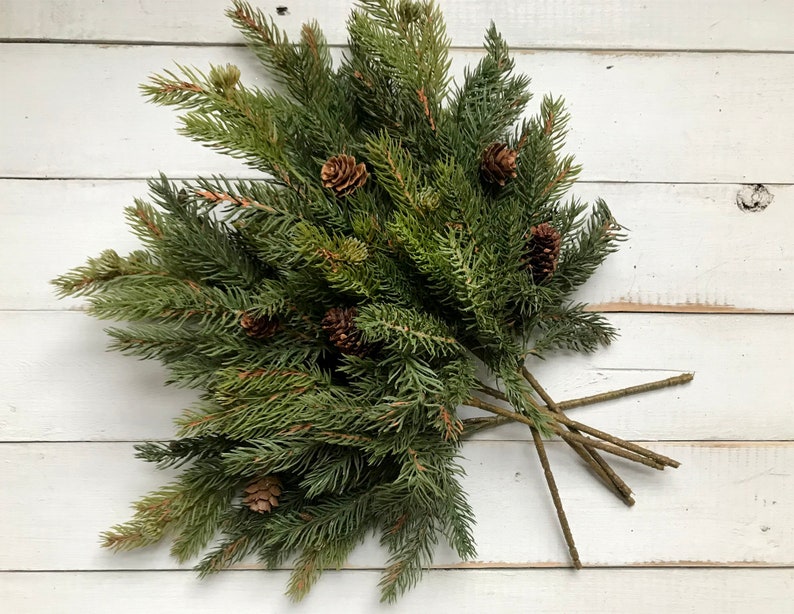 A bouquet of artificial Christmas pine sprays on a farmhouse fence.