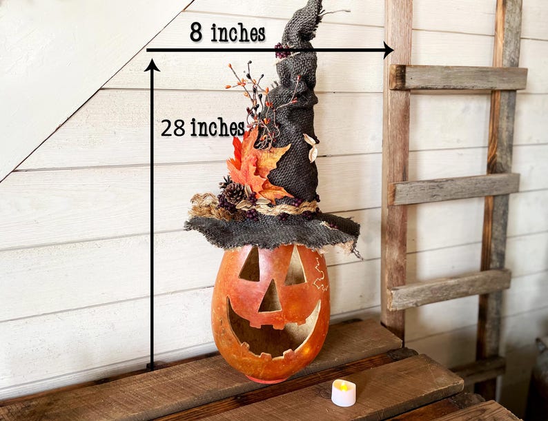 A Large handmade pumpkin witch used for fall decorating. Made from a real dried gourd. The pumpkin, named Hocus Pocus, has a tall burlap crinkled witch hat with a fall leaf arrangement. The gourd measures 28 inches tall and 8 inches wide.