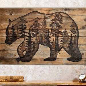Extra large wall art. Made with reclaimed wood, and features a silhouette of a black bear with a forest scene. Artwork is a wood burning by hand. Wood is a weathered brown. The artwork is dark, burned brown.