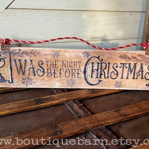 A horizontal wood sign. Twas the night before Christmas and reindeer are wood burned decoratively. The sign hangs with a piece of rope.
