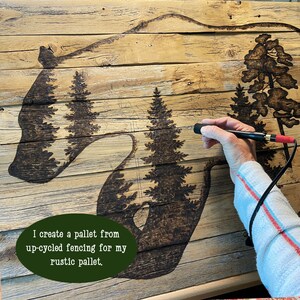 This show me drawing the bear artwork. It is wood burned by hand onto a pallet of reclaimed fence.