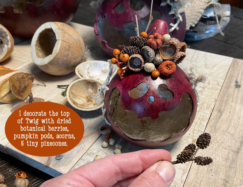 This is a handmade pumpkin decoration. It is a real dried gourd, with a carved ghostly facial expression. I create a fall berry arrangement on the top. I use real dried pods and pinecones.