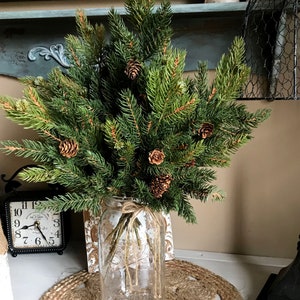 A bouquet of artificial pine sprays in a mason jar for Christmas.
