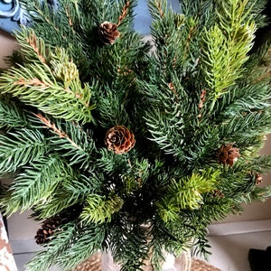 A bouquet of artificial pine sprays in a mason jar for Christmas.