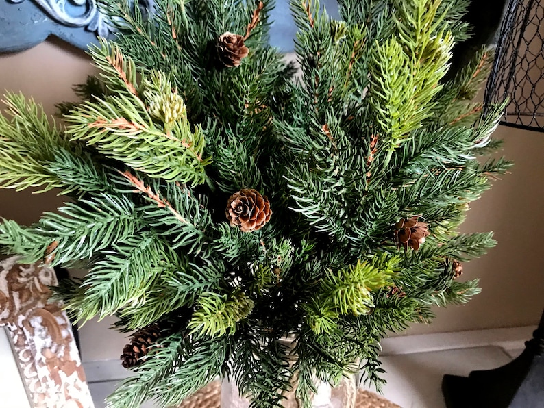 A bouquet of artificial pine sprays in a mason jar for Christmas.