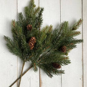 Sprays of artificial Christmas pine sprays on a farmhouse fence.