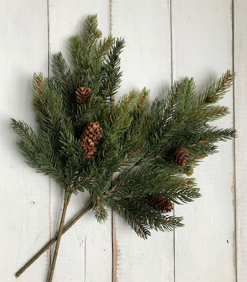 Sprays of artificial Christmas pine sprays on a farmhouse fence.