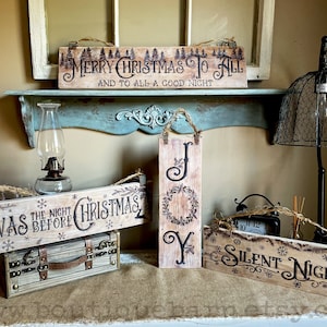 A collection of Christmas signs on reclaimed wood. Signs hang with a piece of rope.