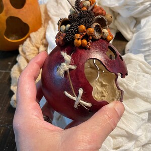 This image shows me holding a fall gourd. I have carved a decorative scare on the side of a little ghost. I stitched the scare up with a hemp cord.