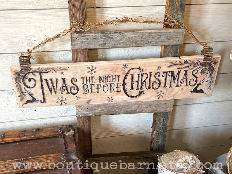 A horizontal wood sign. Twas the night before Christmas and reindeer are wood burned decoratively. The sign hangs with a piece of rope.