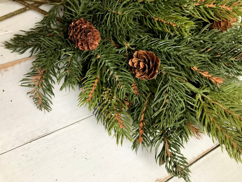 A bouquet of artificial Christmas pine sprays on a farmhouse fence.