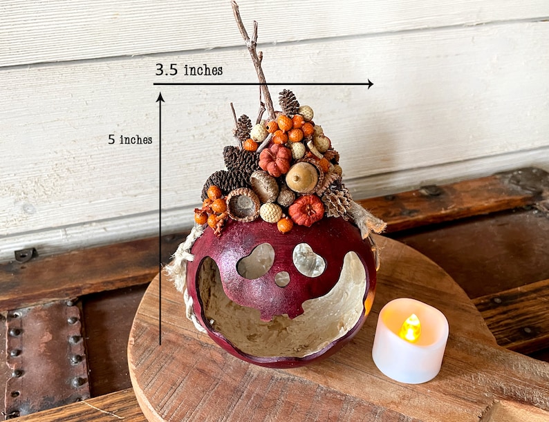 This is a handmade pumpkin decoration. It is a real dried gourd, with a carved ghostly facial expression. The gourd is 5 inches tall and 3.5 inches wide.