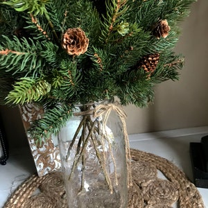 A bouquet of artificial pine sprays in a mason jar for Christmas.