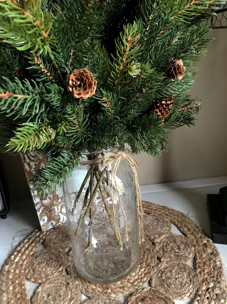 A bouquet of artificial pine sprays in a mason jar for Christmas.