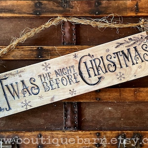 A horizontal wood sign. Twas the night before Christmas and reindeer are wood burned decoratively. The sign hangs with a piece of rope.