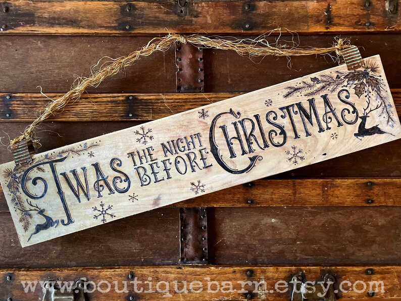 A horizontal wood sign. Twas the night before Christmas and reindeer are wood burned decoratively. The sign hangs with a piece of rope.