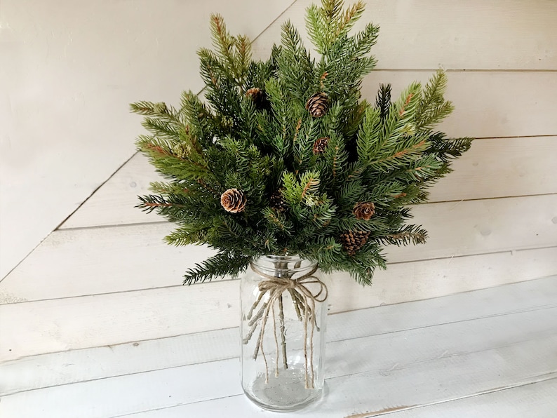 A bouquet of artificial pine sprays in a mason jar for Christmas.