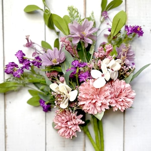 This image shows three faux flower sprays. The bundles feature pink mums, purple daisies, a white hydrangea, and greenery.