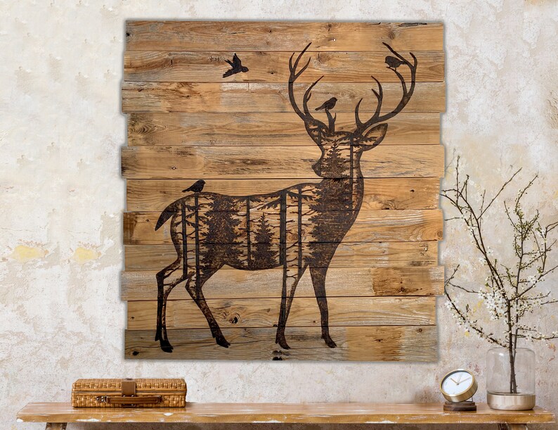 Extra large wall hanging made from reclaimed wood.  It has a dark brown silhouette of a deer with forest scenery inside the body. Birds sit on their antlers. Artwork in wood-burning entirely by hand. The wood is naturally weathered brown.