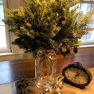 A bouquet of artificial pine sprays in a mason jar for Christmas.