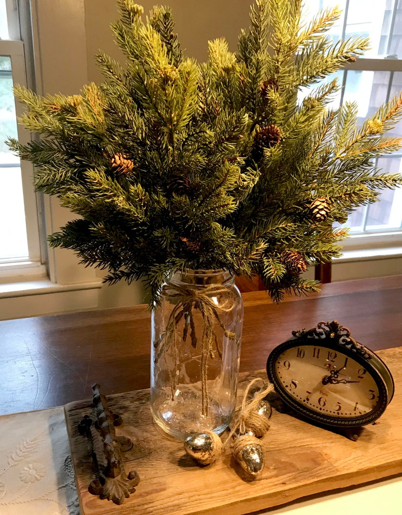 A bouquet of artificial pine sprays in a mason jar for Christmas.
