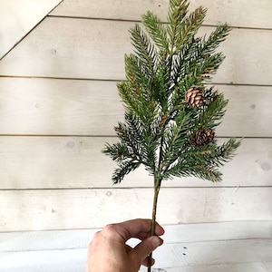 A spray off artificial Christmas pine sprays on a farmhouse fence.