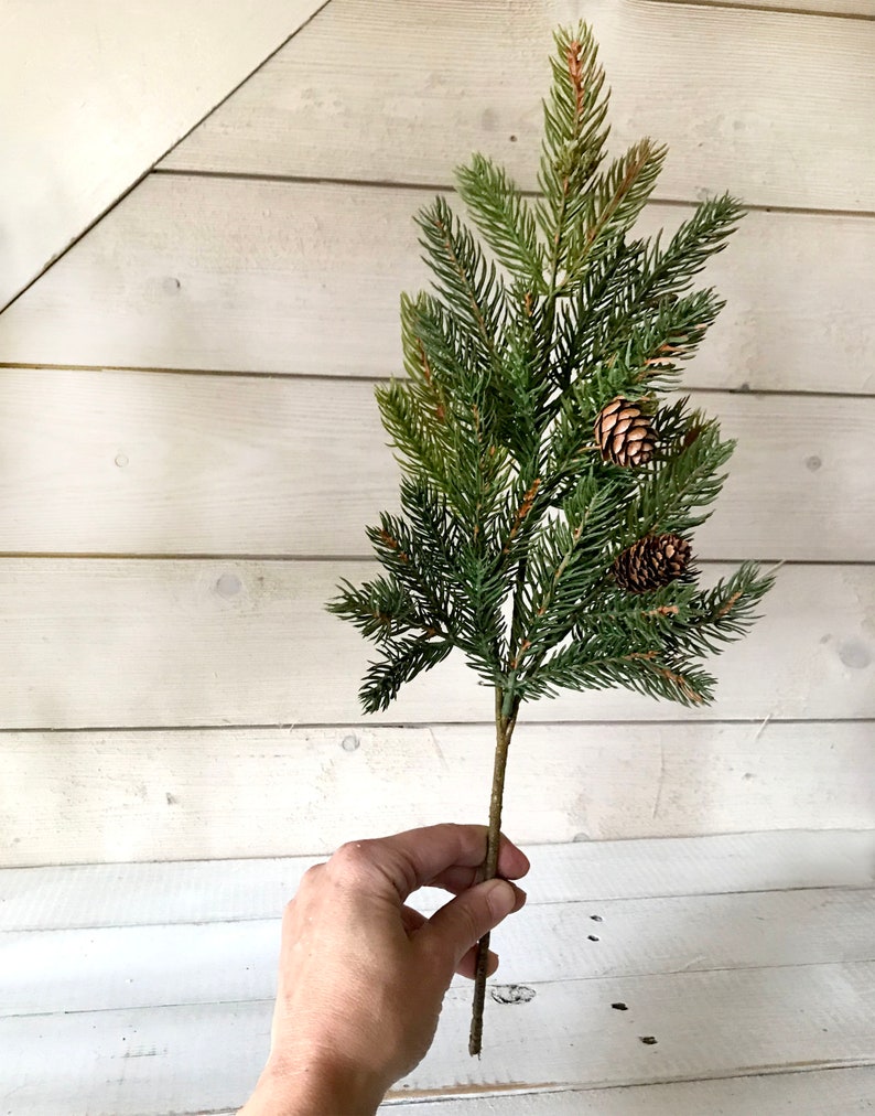 A spray off artificial Christmas pine sprays on a farmhouse fence.