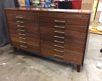 Könnte beinhalten: Eine große, dunkelbraune Kommode aus Holz mit 14 Schubladen und silbernen Schubladengriffen. Die Kommode hat ein schlichtes, modernes Design und ist aus massivem Holz gefertigt.