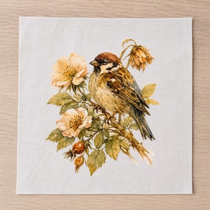 May include: A square white fabric napkin featuring a detailed watercolor illustration of a brown and tan sparrow perched on a branch with pale yellow flowers, green leaves, and small orange rose hips, centered on the light-colored textile surface.