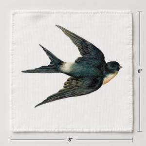 Peut inclure: Un carré de tissu blanc orné d'une illustration détaillée d'une hirondelle bleu foncé en plein vol. L'oiseau présente une gorge claire et des ailes pointues. Le carré mesure 20,32 cm sur 20,32 cm, comme indiqué par les lignes de mesure.