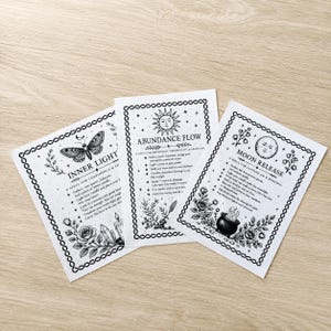 May include: Three rectangular white cards with black ink illustrations and text. The cards feature titles Inner Light, Abundance Flow, and Moon Release, surrounded by decorative borders with celestial, floral, and mystical graphic elements.