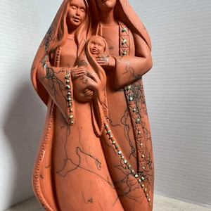 Puede incluir: Escultura de terracota de la Sagrada Familia. Las figuras est&aacute;n representadas con ropa tradicional y detalles en turquesa. La escultura est&aacute; pintada a mano con l&iacute;neas negras y detalles.