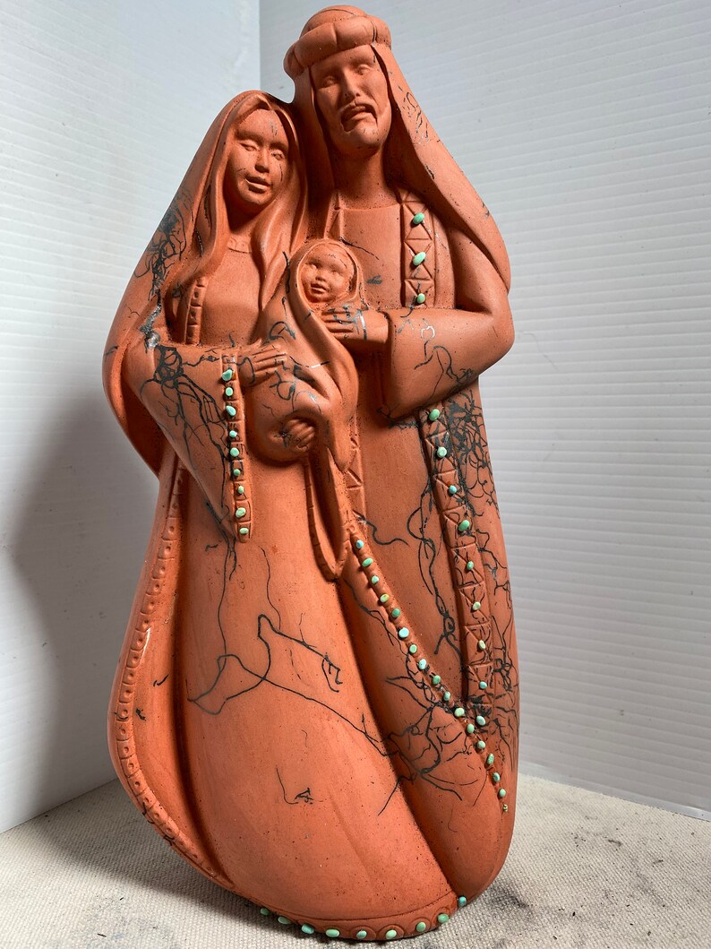 Puede incluir: Escultura de terracota de la Sagrada Familia. Las figuras est&aacute;n representadas con ropa tradicional y detalles en turquesa. La escultura est&aacute; pintada a mano con l&iacute;neas negras y detalles.