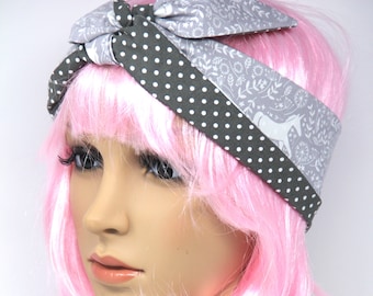 May include: A gray and white headband with a polka dot pattern and a floral design. The headband is tied in a knot at the top.