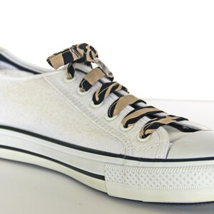 May include: White canvas low-top sneakers with black and brown patterned shoelaces.