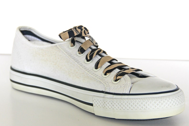 May include: White canvas low-top sneakers with black and brown patterned shoelaces.