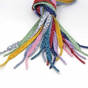 May include: A bundle of colorful shoelaces with a floral pattern. The shoelaces are made of fabric and are tied together at the top.