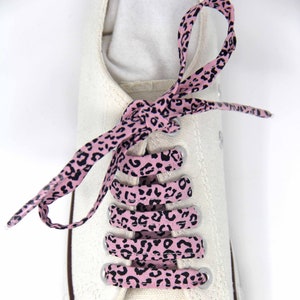 K&ouml;nnte beinhalten: Rosa-schwarze Schn&uuml;rsenkel mit Leopardenmuster, die an einem wei&szlig;en Canvas-Schuh gebunden sind.