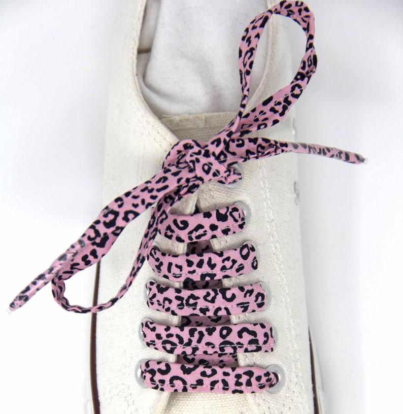 K&ouml;nnte beinhalten: Rosa-schwarze Schn&uuml;rsenkel mit Leopardenmuster, die an einem wei&szlig;en Canvas-Schuh gebunden sind.