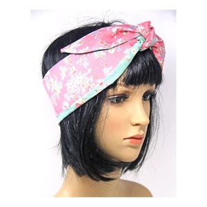 May include: A pink and green floral headband with a tied bow on top. The headband is made of fabric and has a floral pattern.