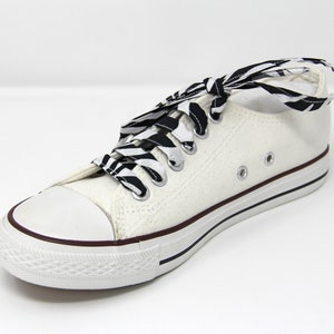 May include: White canvas low-top sneakers with black and white zebra print shoelaces.
