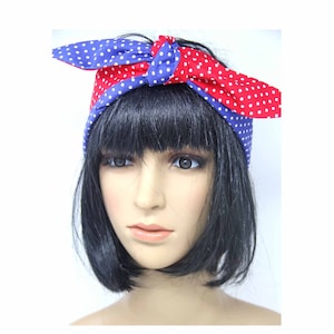 May include: A red and blue headband with white polka dots. The headband is tied in a bow at the top of the head.