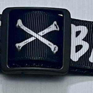 May include: Black dog collar with white text that reads "BAD to the BONE". The collar has a black buckle with a white crossed bone design. The collar is made of a durable, woven material.