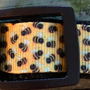 May include: A yellow and black dog collar with a bee pattern and a black buckle.