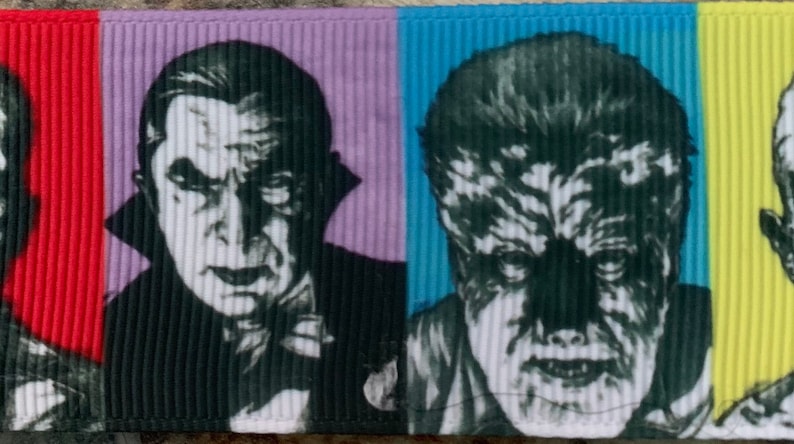 Puede incluir: Una cinta de tela colorida con im&aacute;genes en blanco y negro de monstruos cl&aacute;sicos de pel&iacute;culas de terror. La cinta presenta a Dr&aacute;cula, el Hombre Lobo, el Monstruo de Frankenstein y la Criatura de la Laguna Negra.